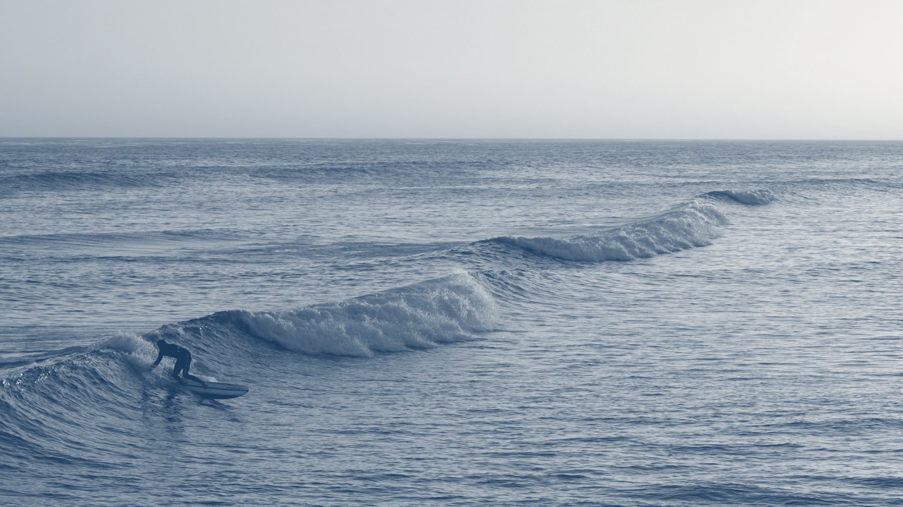 A surfer riding a wave at sunset.